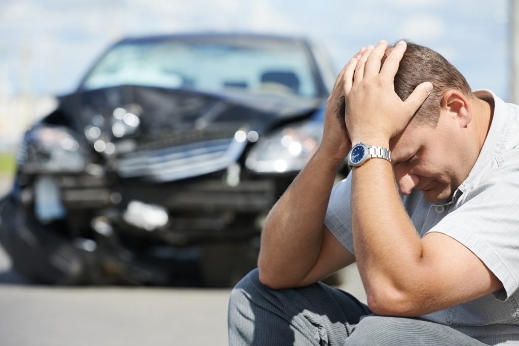 Upset man in front of a car accident