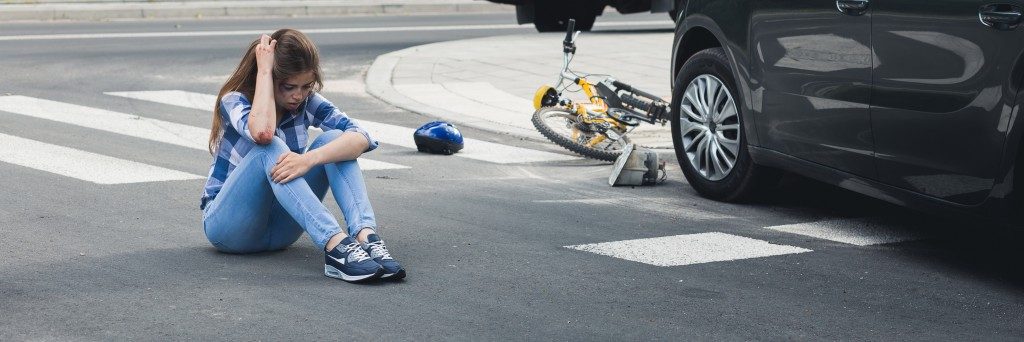 woman sitting on the road after a car accident