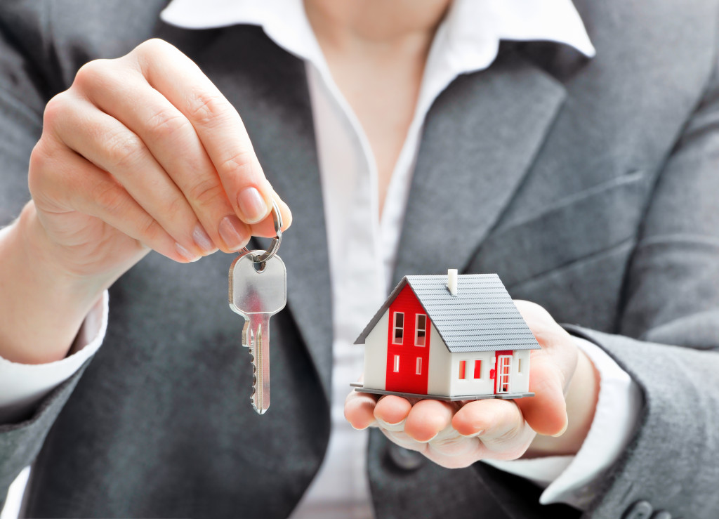 real estate agent holding house key and a miniature house